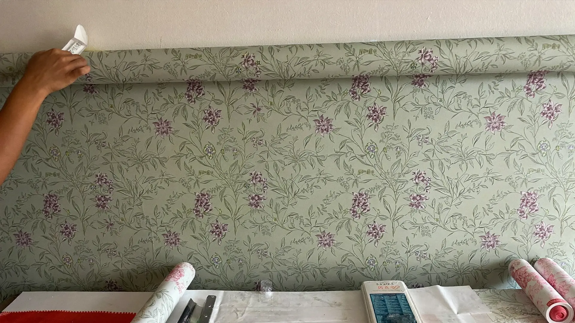 Colocación de una tira de papel pintado con espátula de alisado en Terrassa