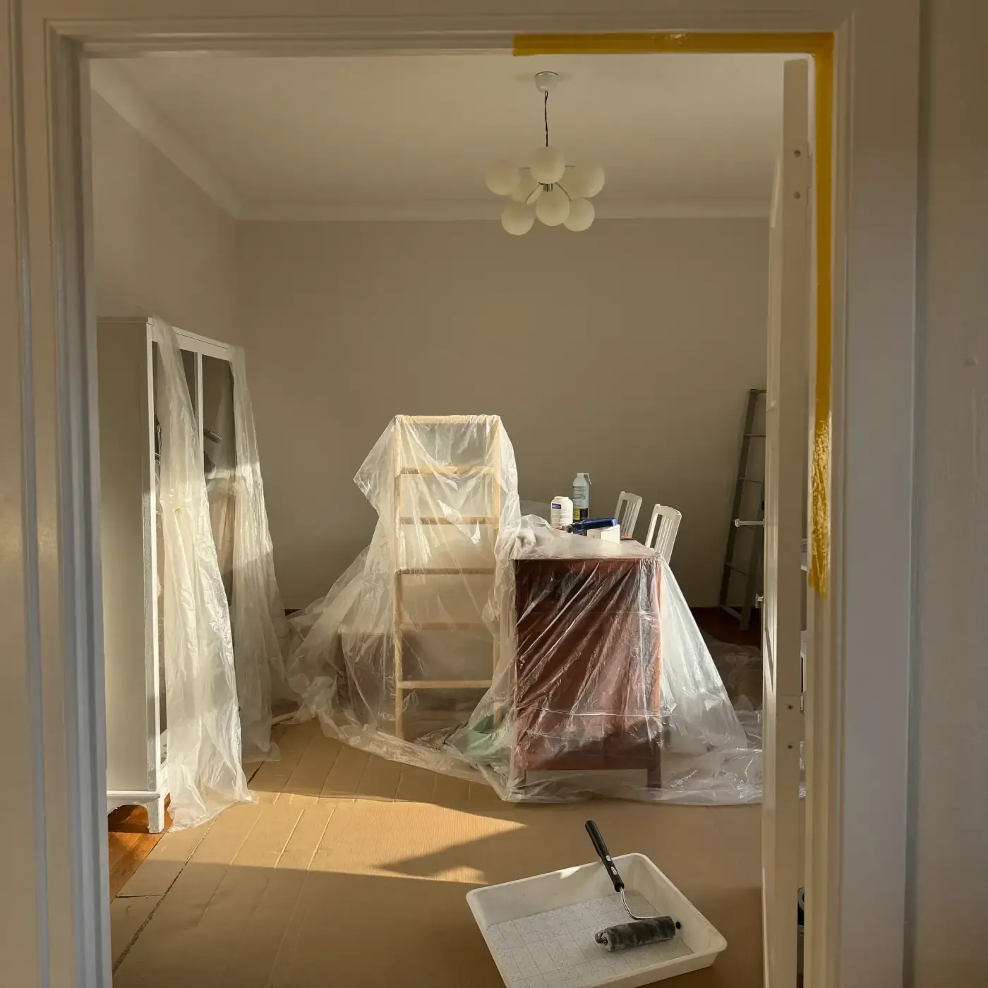 Habitación preparada para pintar con muebles cubiertos de plástico