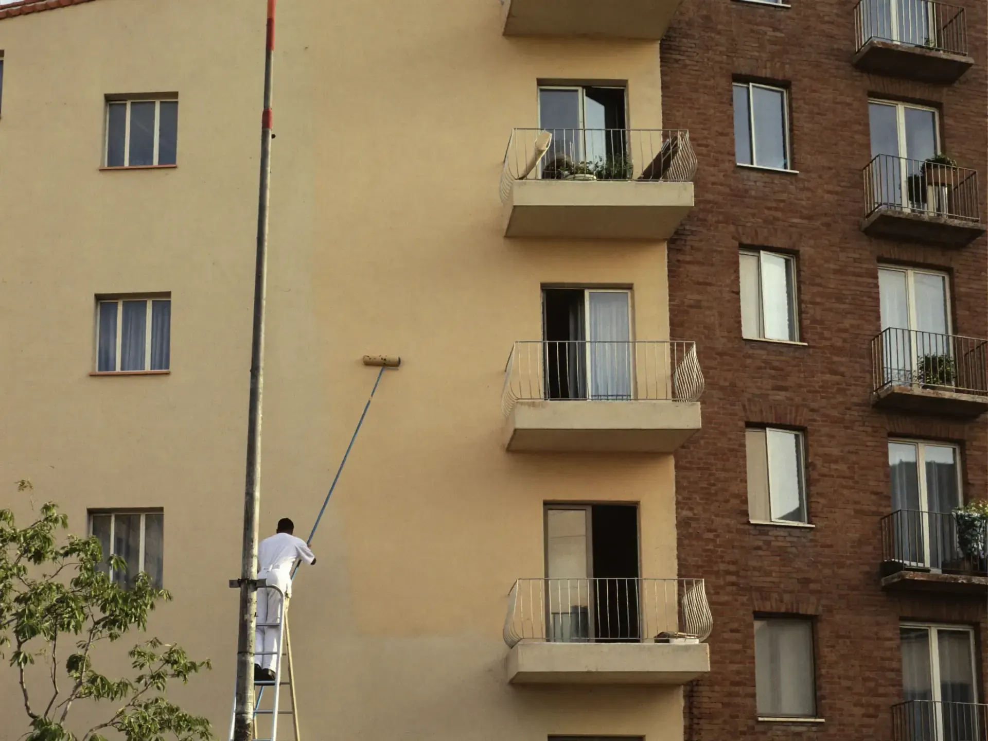 Pintor en andamio pintando fachada de edificio español